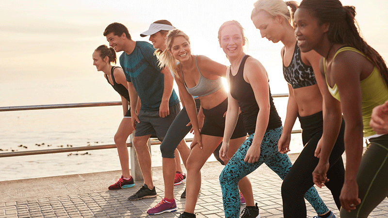 Group of people smiling on the beach preparing for a race